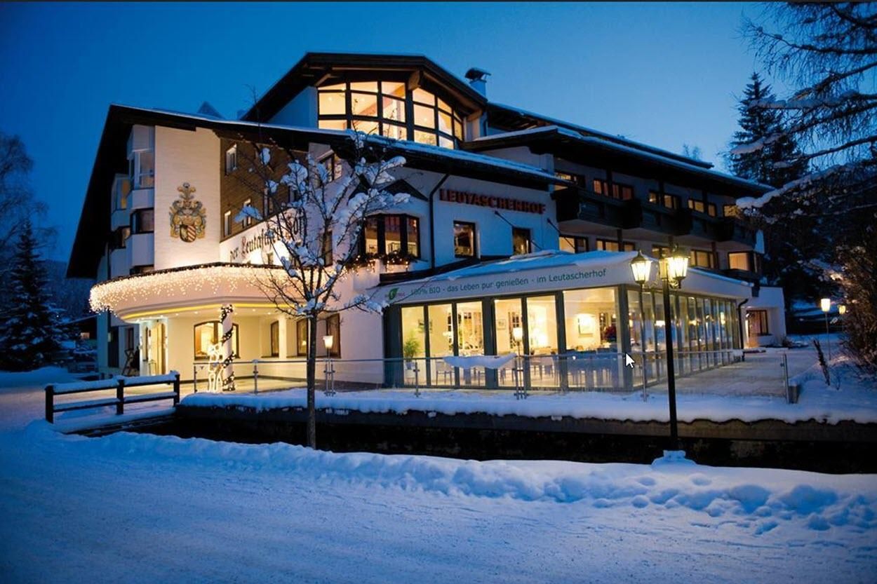 A cozy hotel in the winter snow, illuminated by warm light. The surroundings are peaceful and inviting.