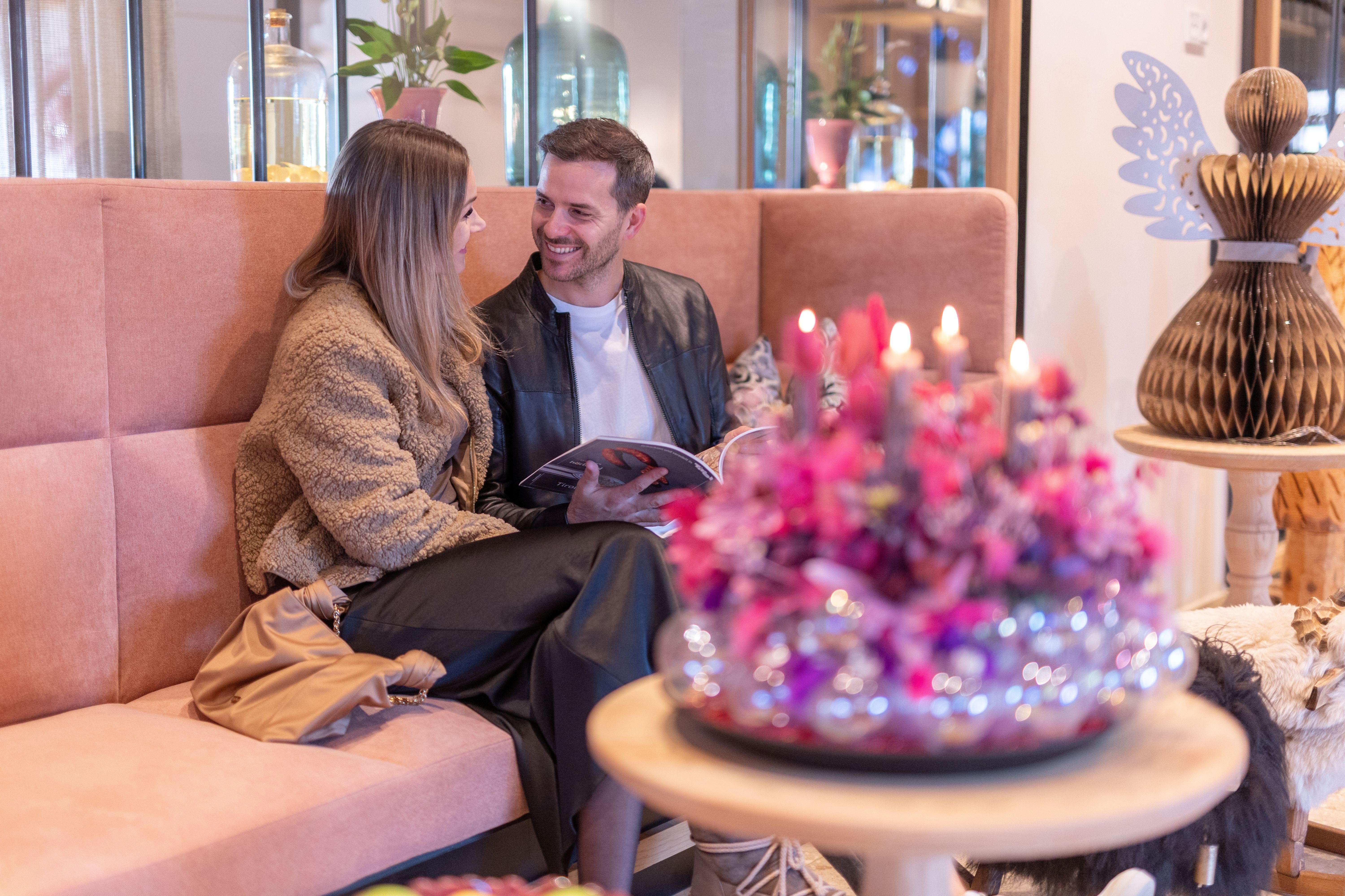 A cozy café setting with a couple conversing and smiling. In the foreground, there is a lovely bouquet of flowers on a table.