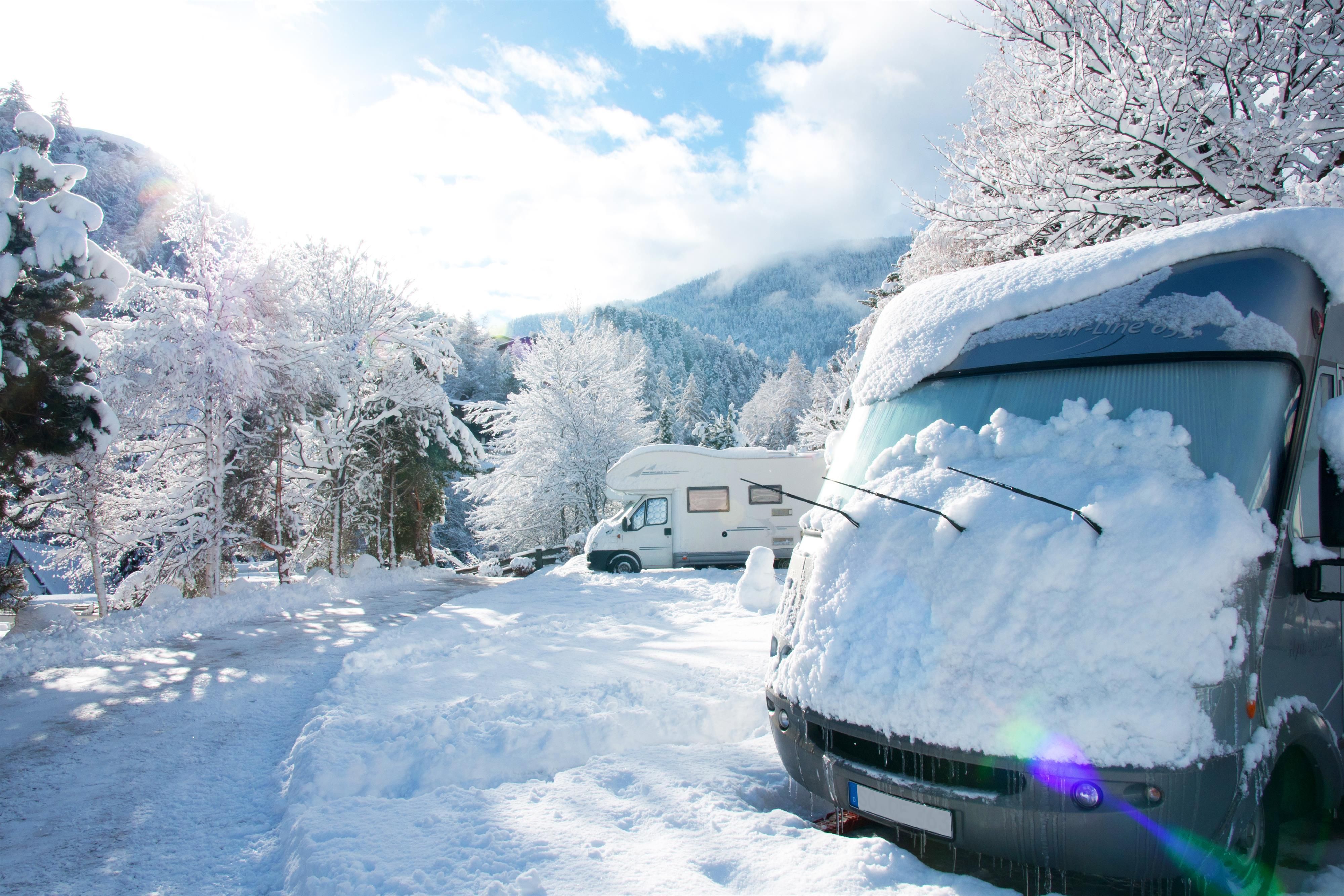 A motorhome in the snow, surrounded by winter trees. The scene exudes tranquility and cold.