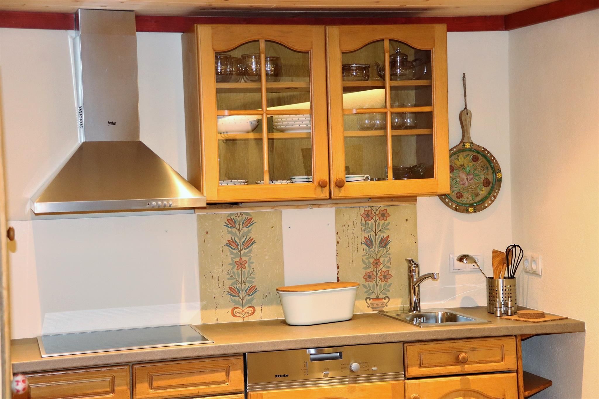 A modern kitchen with wooden cabinets and a stainless steel stove. The space is bright and inviting with decorative elements.