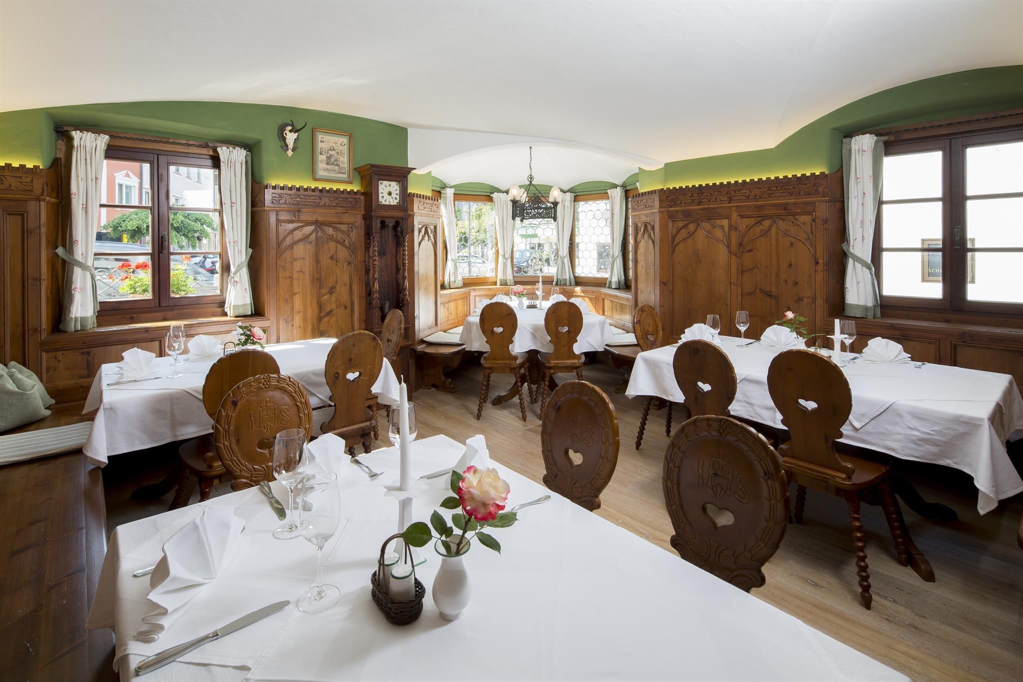 A cozy restaurant with wooden decor and beautifully set tables. The windows offer a view of the outdoors and create an inviting atmosphere.