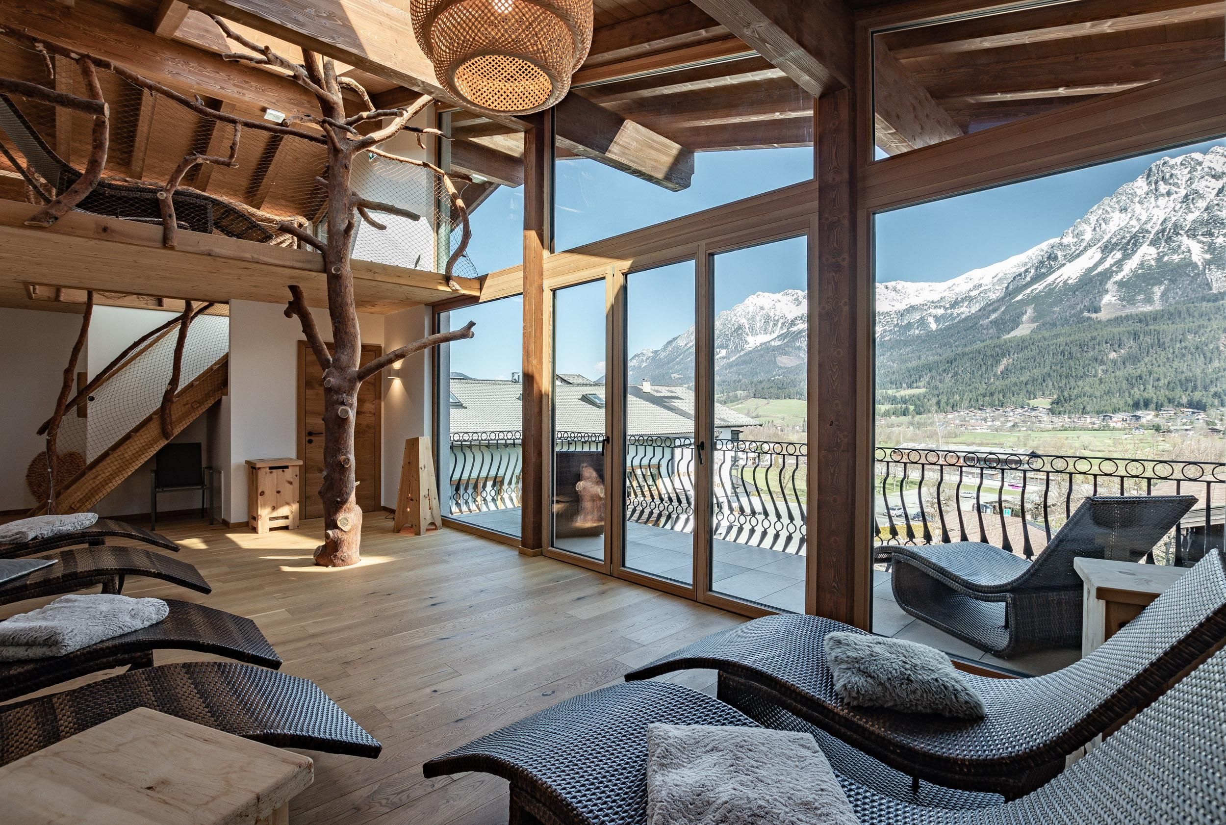 A modern relaxation room with large windows and a view of the mountains. The furniture is made of wood and provides a cozy atmosphere.