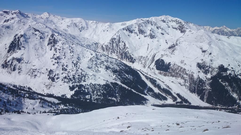 A breathtaking mountain panorama with snow-capped peaks. The landscape showcases a serene winter idyll under a clear blue sky.
