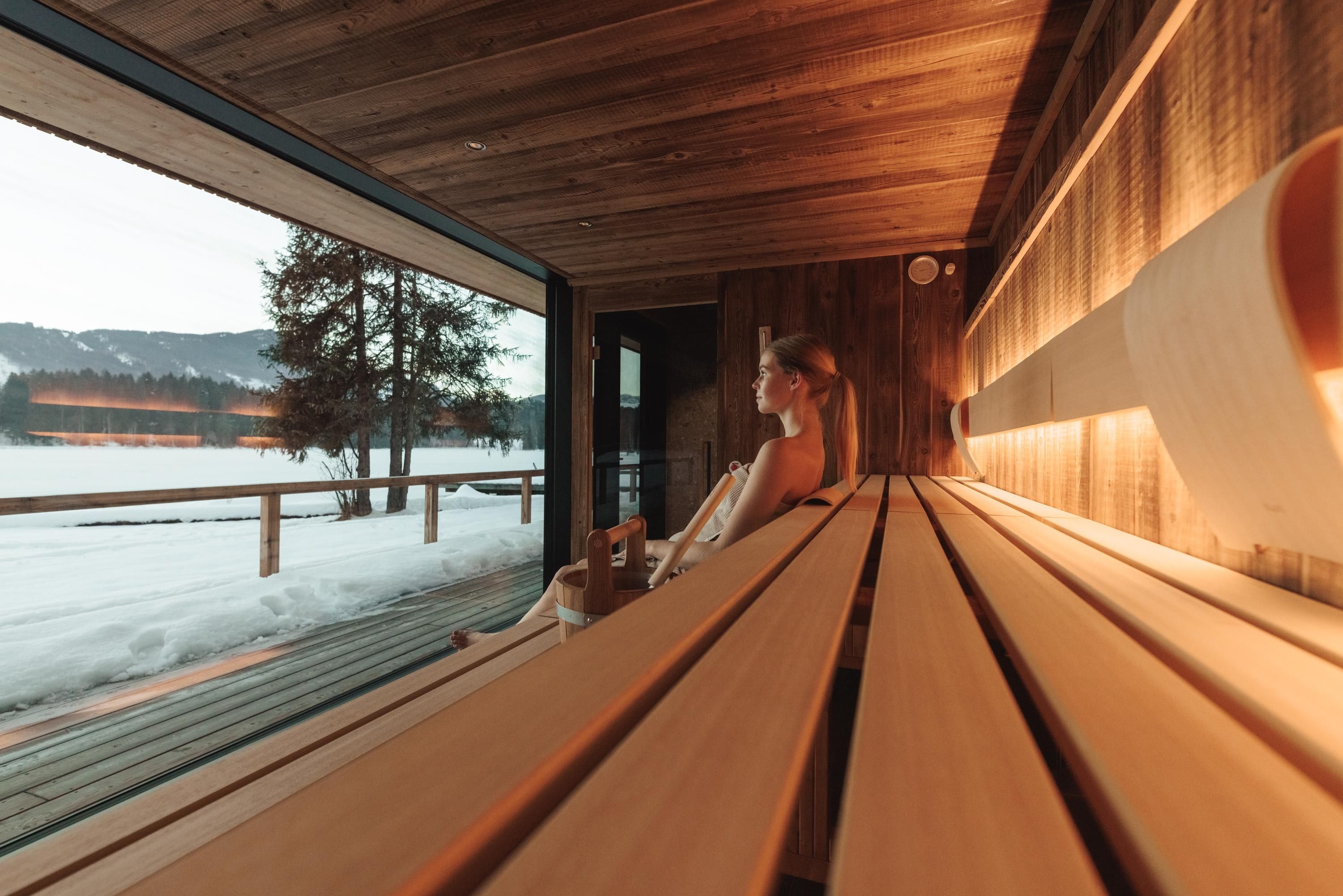 <p>A modern sauna interior with wooden benches and large windows. In the background, a winter landscape with snow and trees can be seen.</p>