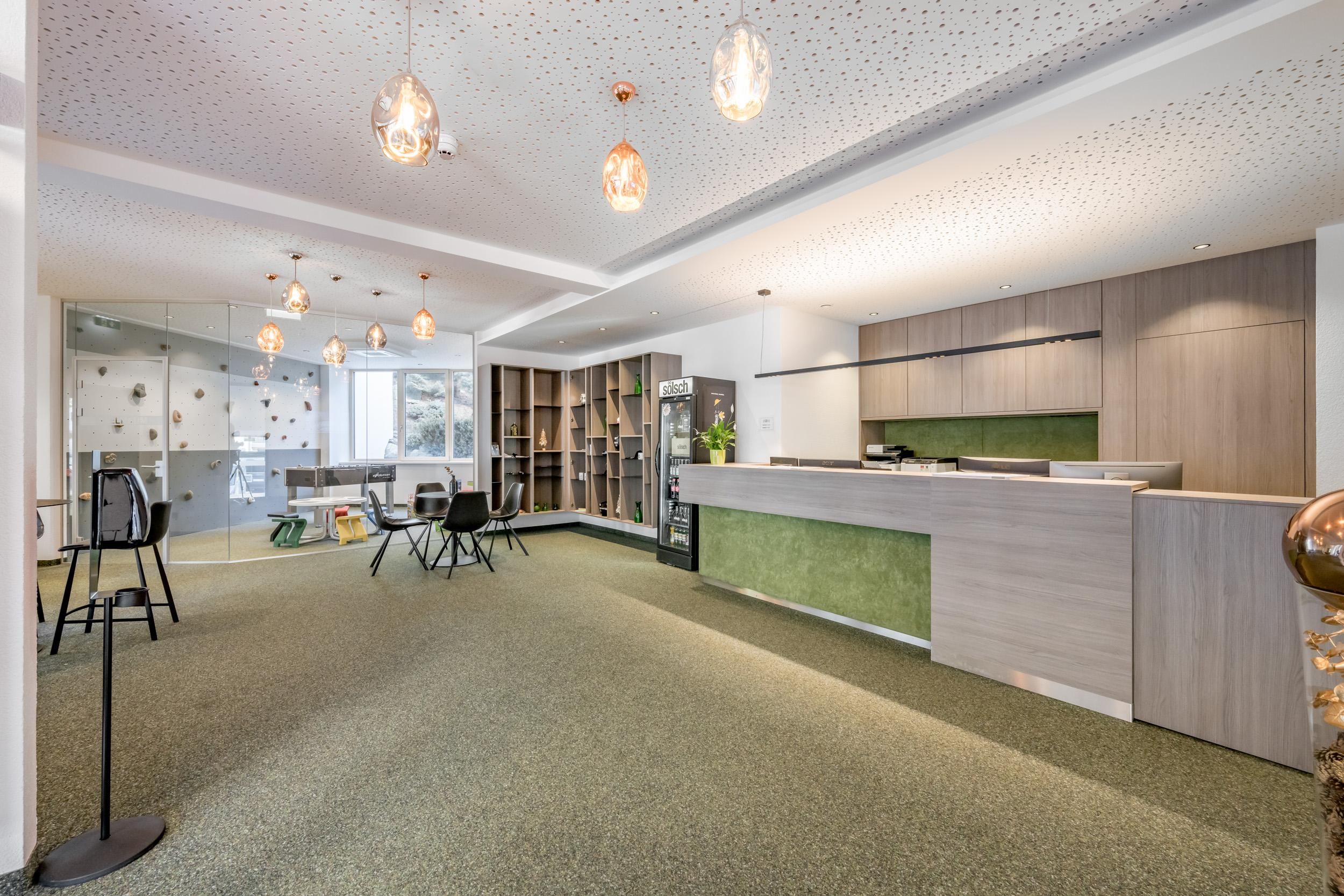 A modern reception area with a stylish reception desk and cozy seating. The space is bright and inviting, with green accents and beautiful light sources.