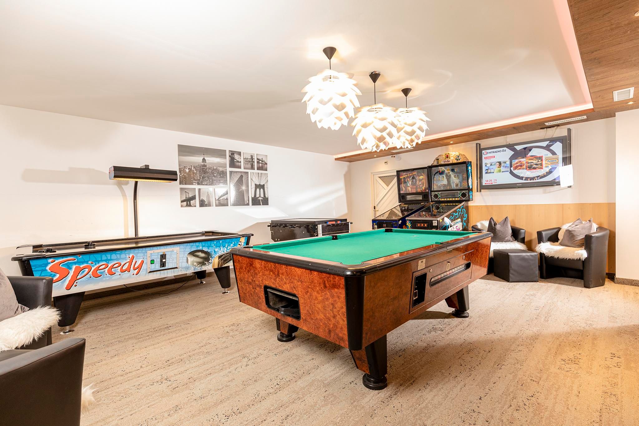A game room with a billiard table and an air hockey table. Cozy seating and modern lighting create an inviting atmosphere.