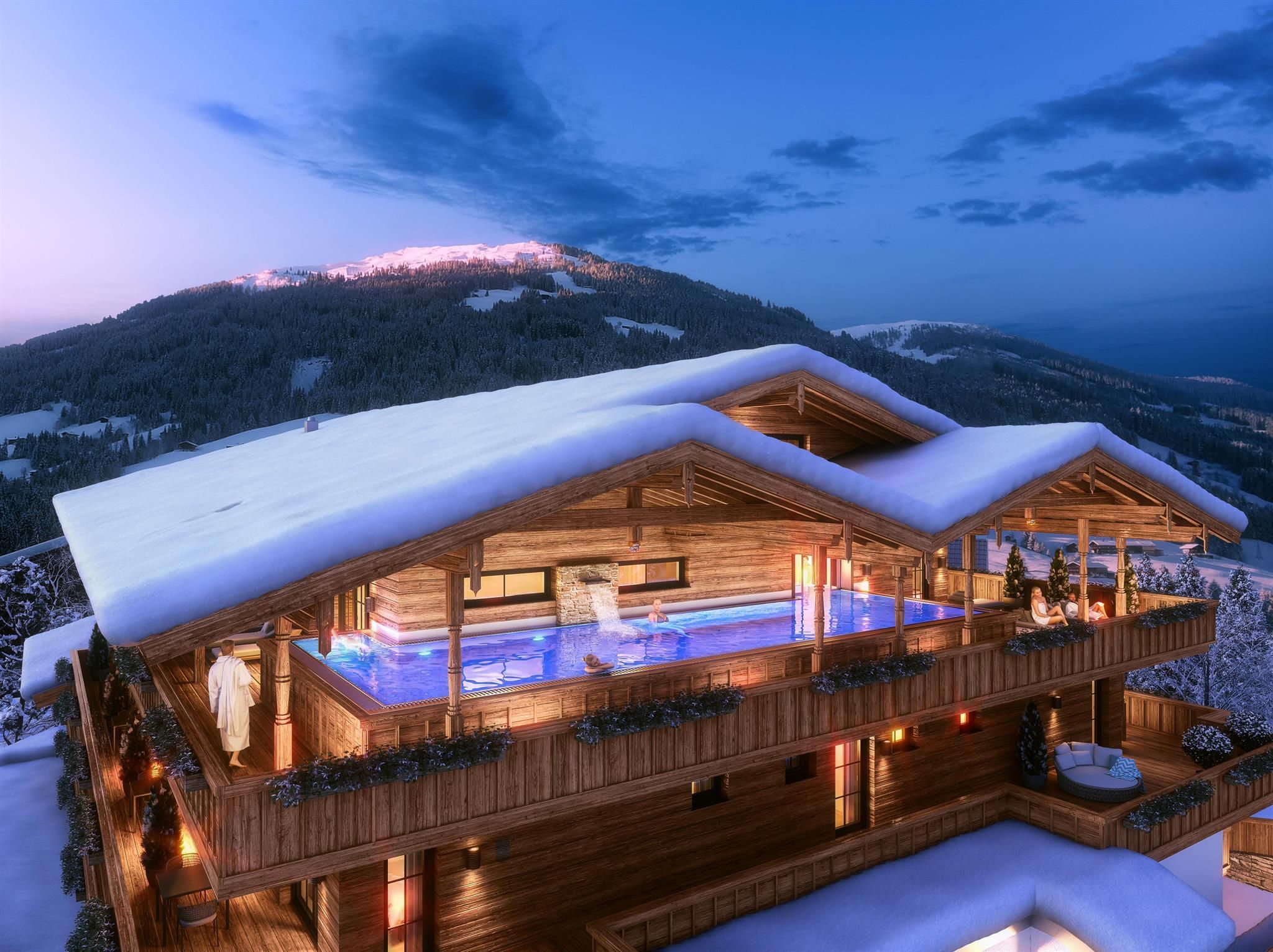 A cozy wooden house in the snow with a swimming pool on the terrace. The surroundings feature snow-covered mountains and a clear evening sky.