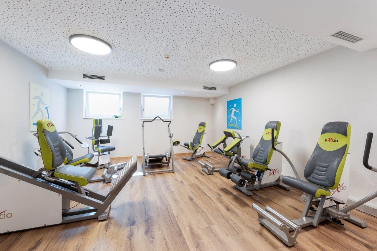 A modern equipped training room with several fitness machines. The floor is made of wood, and the walls are designed to be bright and friendly.