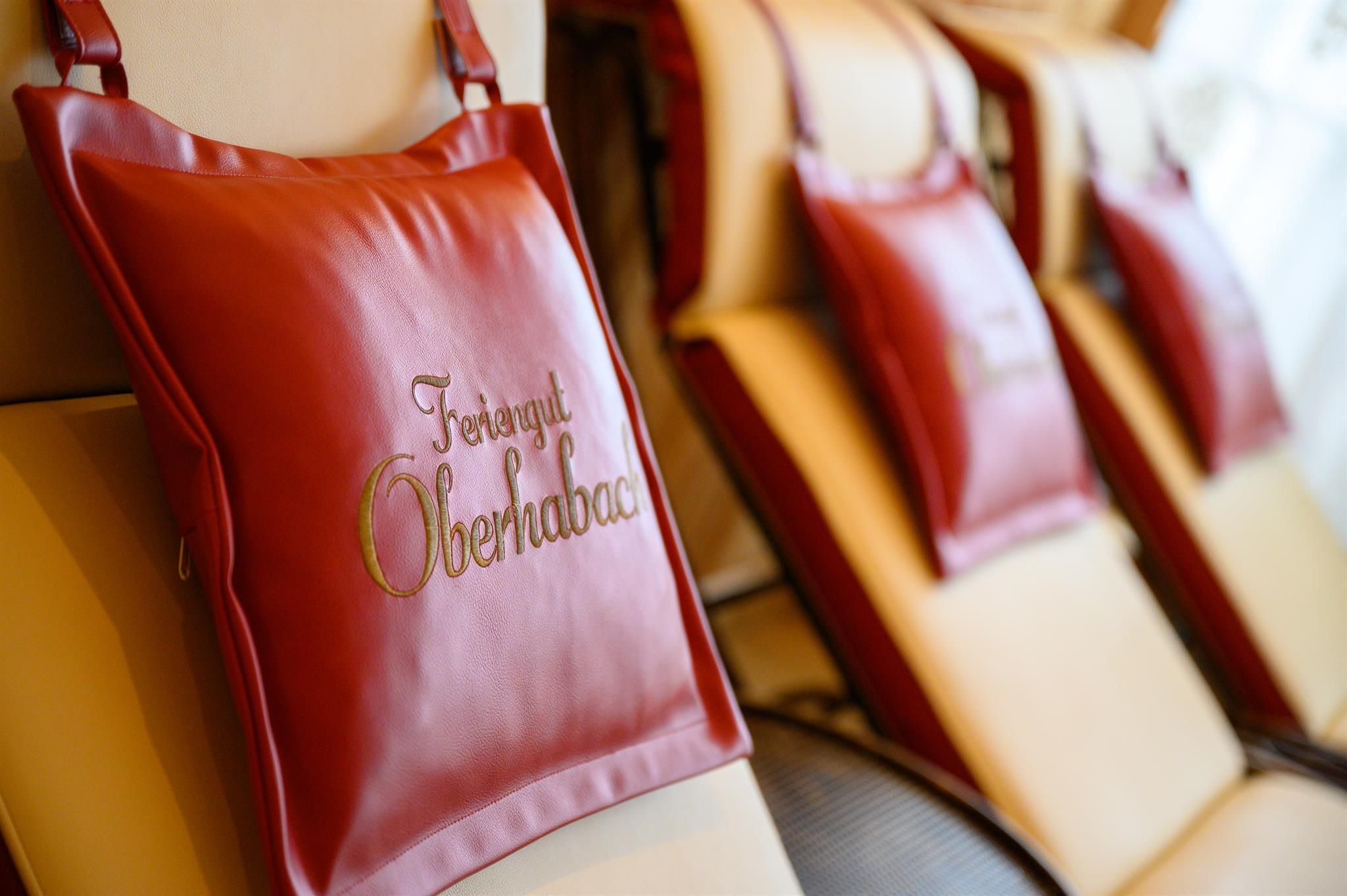 Red cushions with golden lettering on beige loungers. The space feels relaxing and inviting.