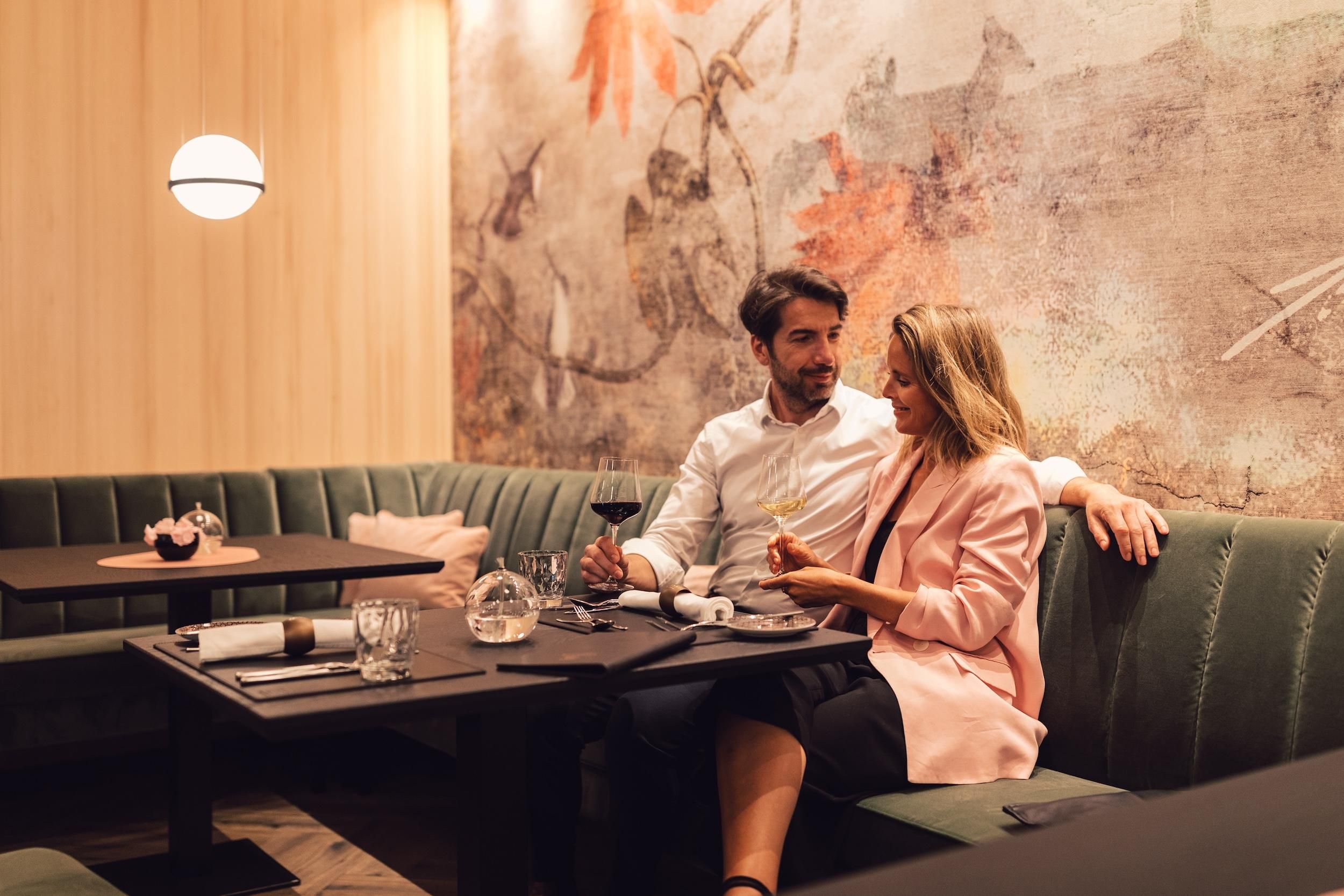 A modern restaurant with a cozy atmosphere. A couple is sitting together at a table enjoying a romantic dinner.