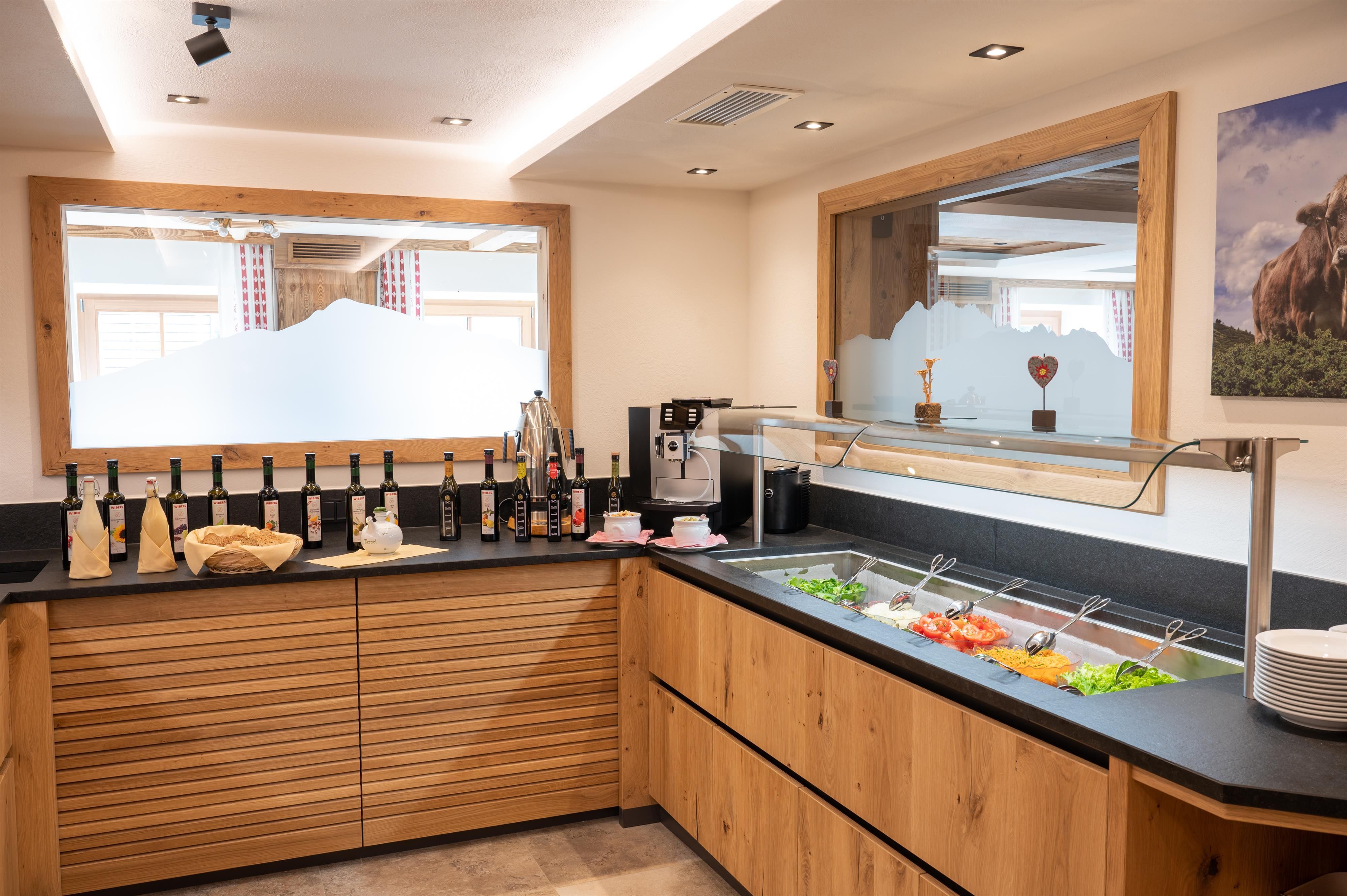 An inviting buffet area with fresh salads and vegetables. In the background, bottles and some decorative items are placed on a wooden shelf.