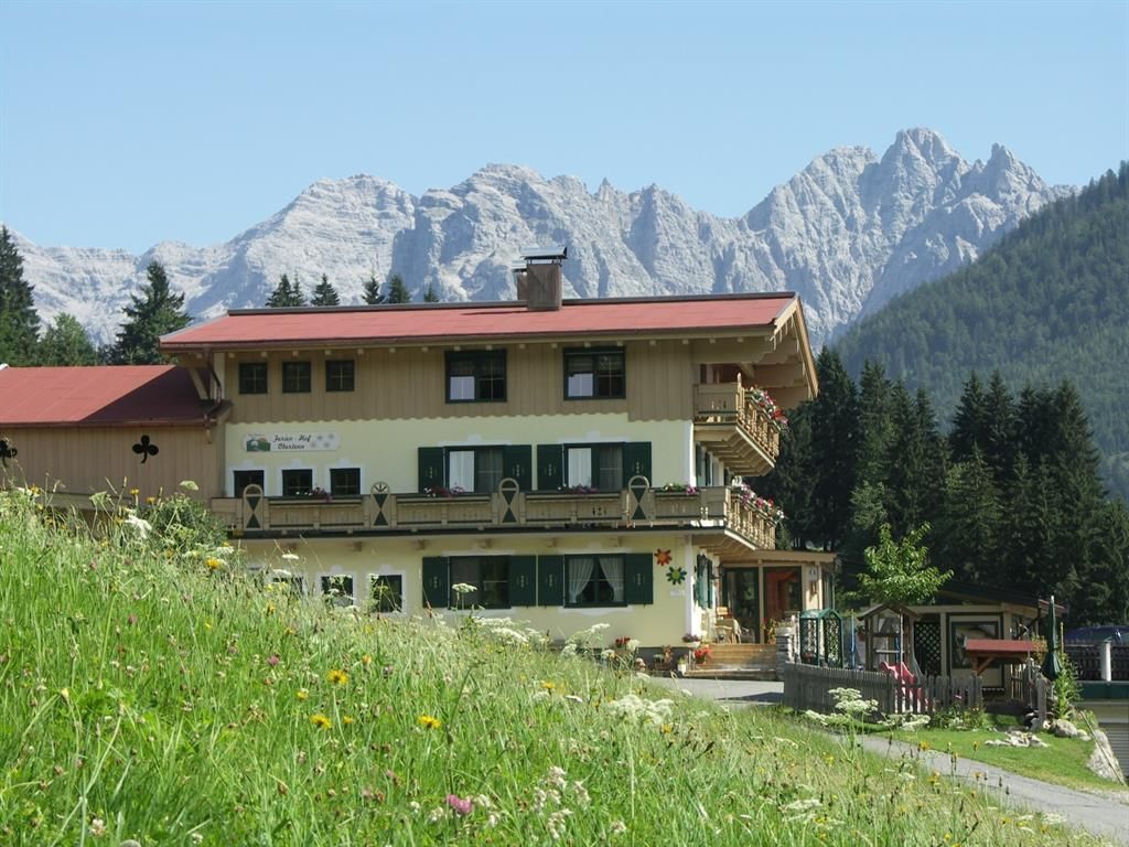 A charming house in the midst of a green meadow, surrounded by majestic mountains. The clear sky gives the scene a peaceful atmosphere.