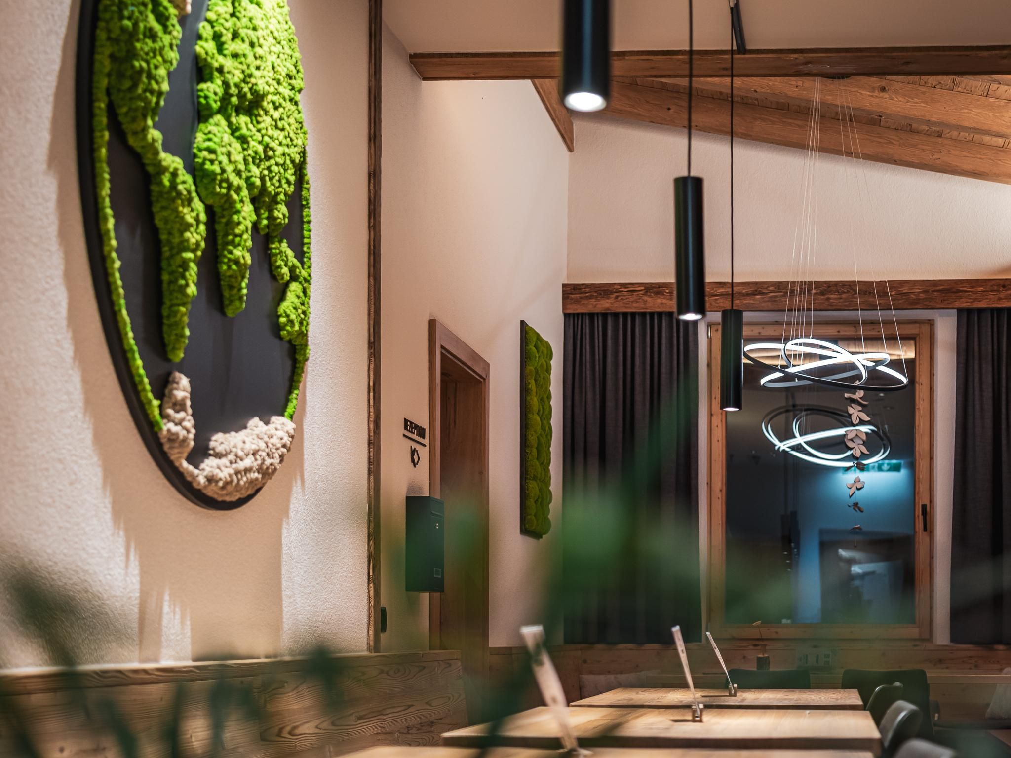 A modern restaurant with stylish interior. Green moss wall decorations and elegant lighting create an inviting atmosphere.