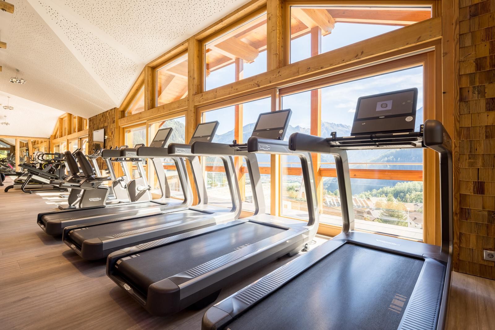 A modern gym with treadmills and large windows.
A lot of sunlight streams in and provides a beautiful view of the landscape.