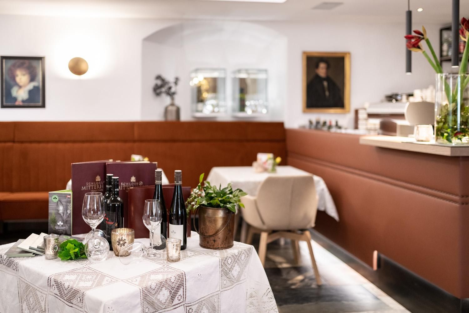 An elegant restaurant with stylishly set tables and a cozy atmosphere. The walls are adorned with modern and classical artworks.