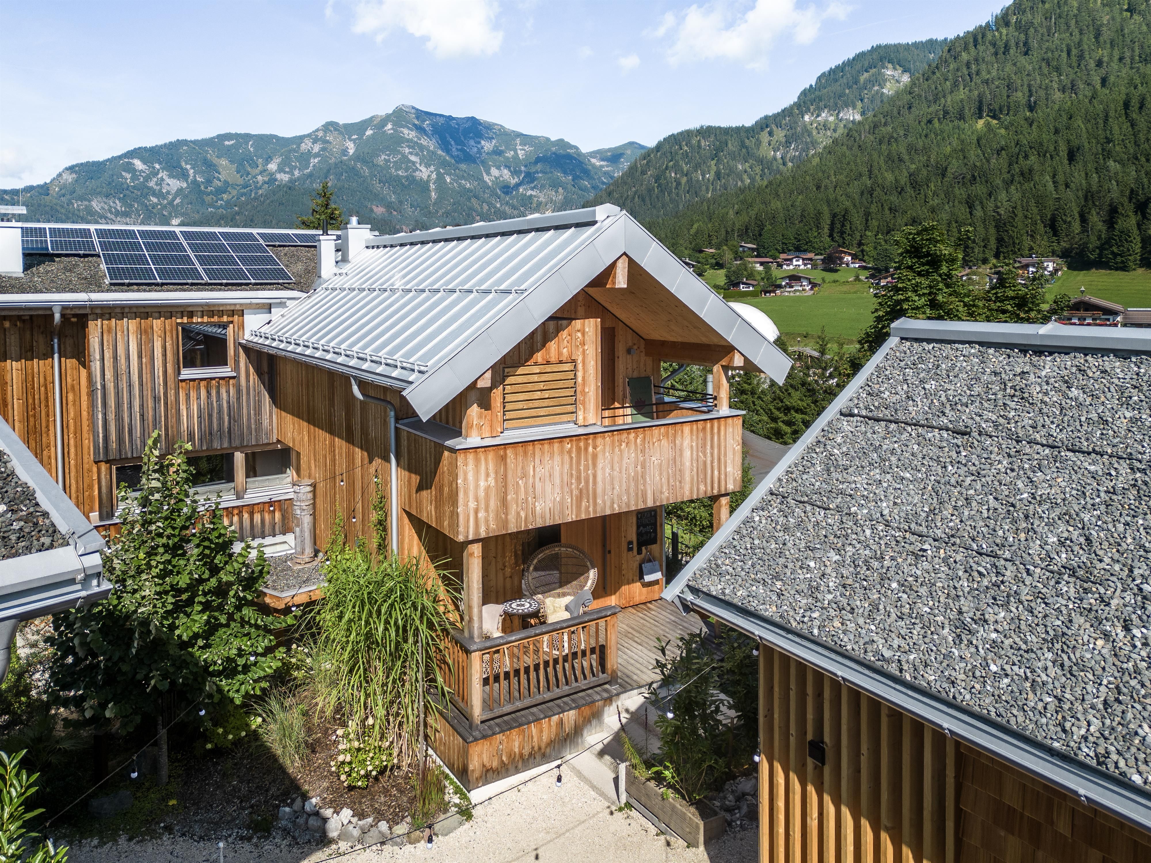 A modern wooden house with a balcony and a beautiful environment. The mountains and trees in the background create an idyllic atmosphere.
