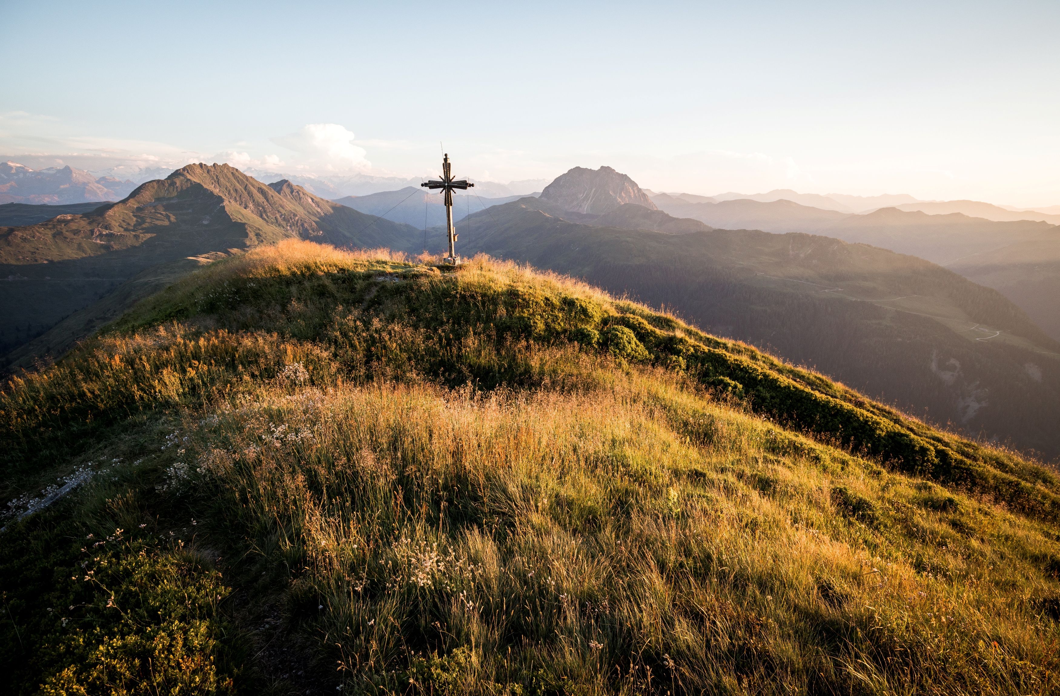 Schwarzkogel in den Kitzbüheler Alpen, Gipfelkreuz bei Sonnenuntergangsstimmung mit Rettenstein im Hintergrund