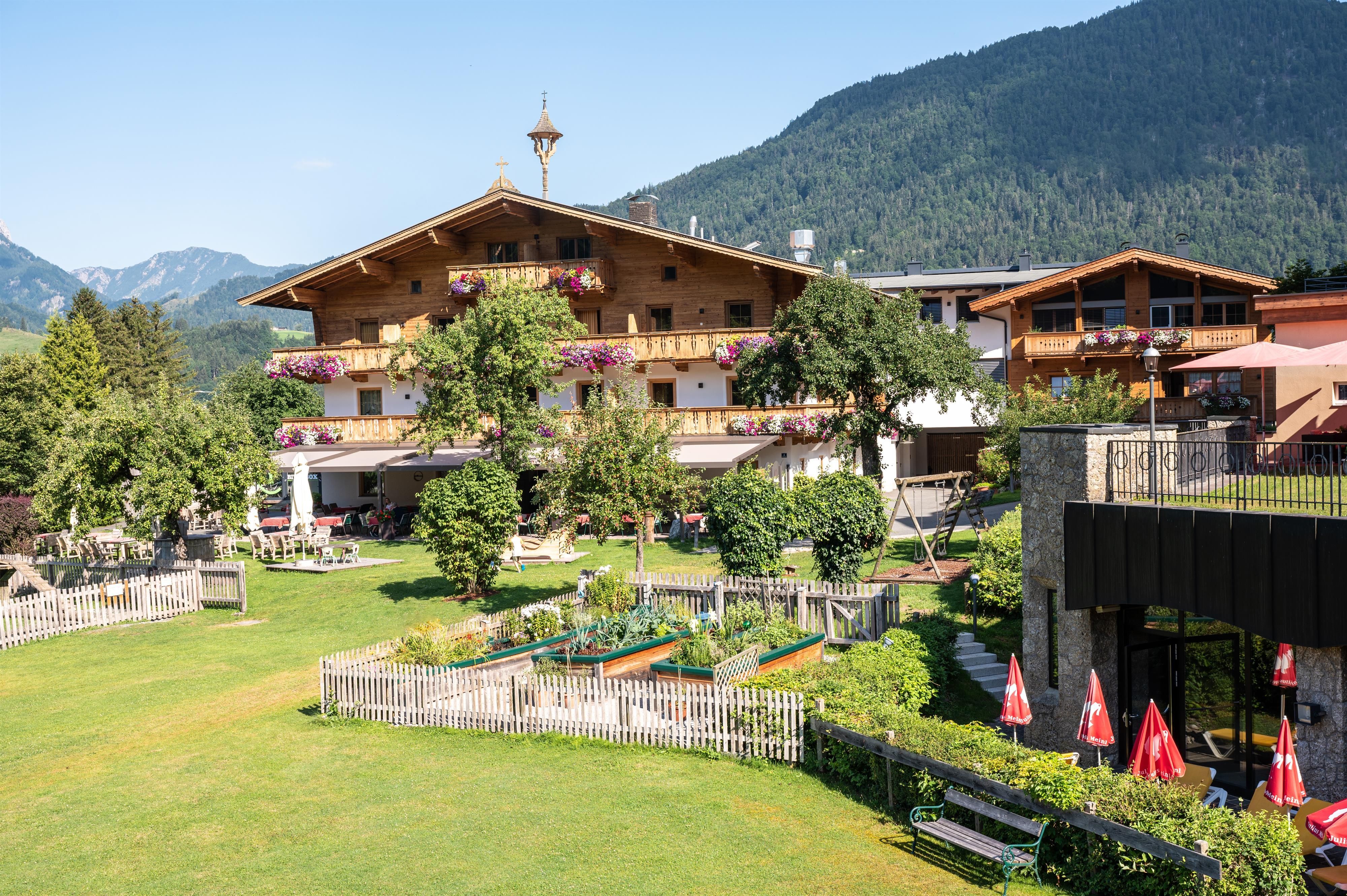 A picturesque hotel in the mountains with a large garden. The surroundings are green and inviting, perfect for relaxation and nature experiences.
