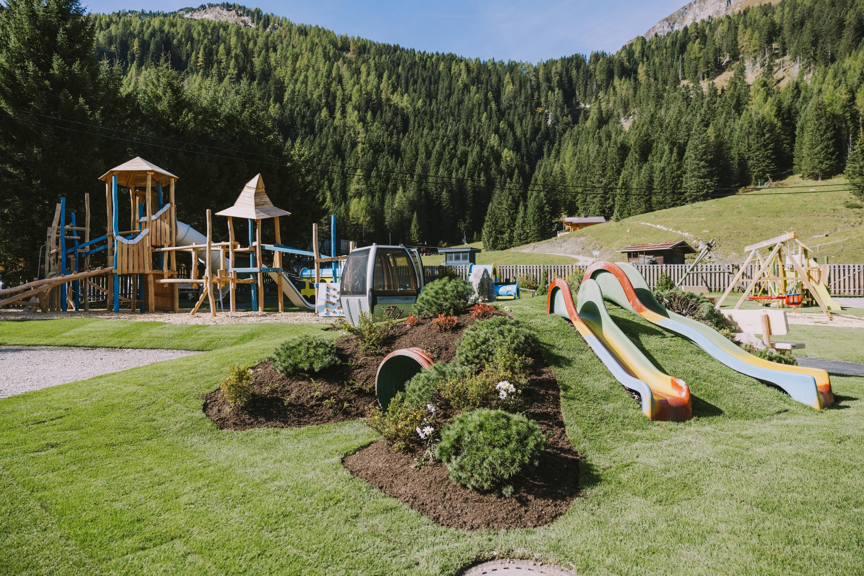 A beautiful playground in nature with slides and play equipment. Surrounded by green meadows and mountains.