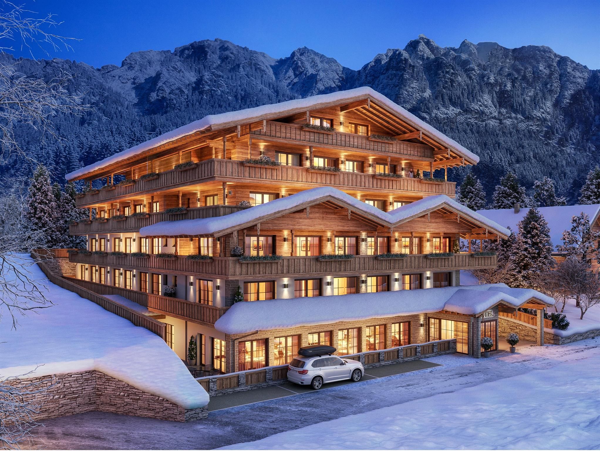 A charming wooden building in alpine style, surrounded by snow and mountains. The hotel is illuminated in the evening and radiates a cozy atmosphere.