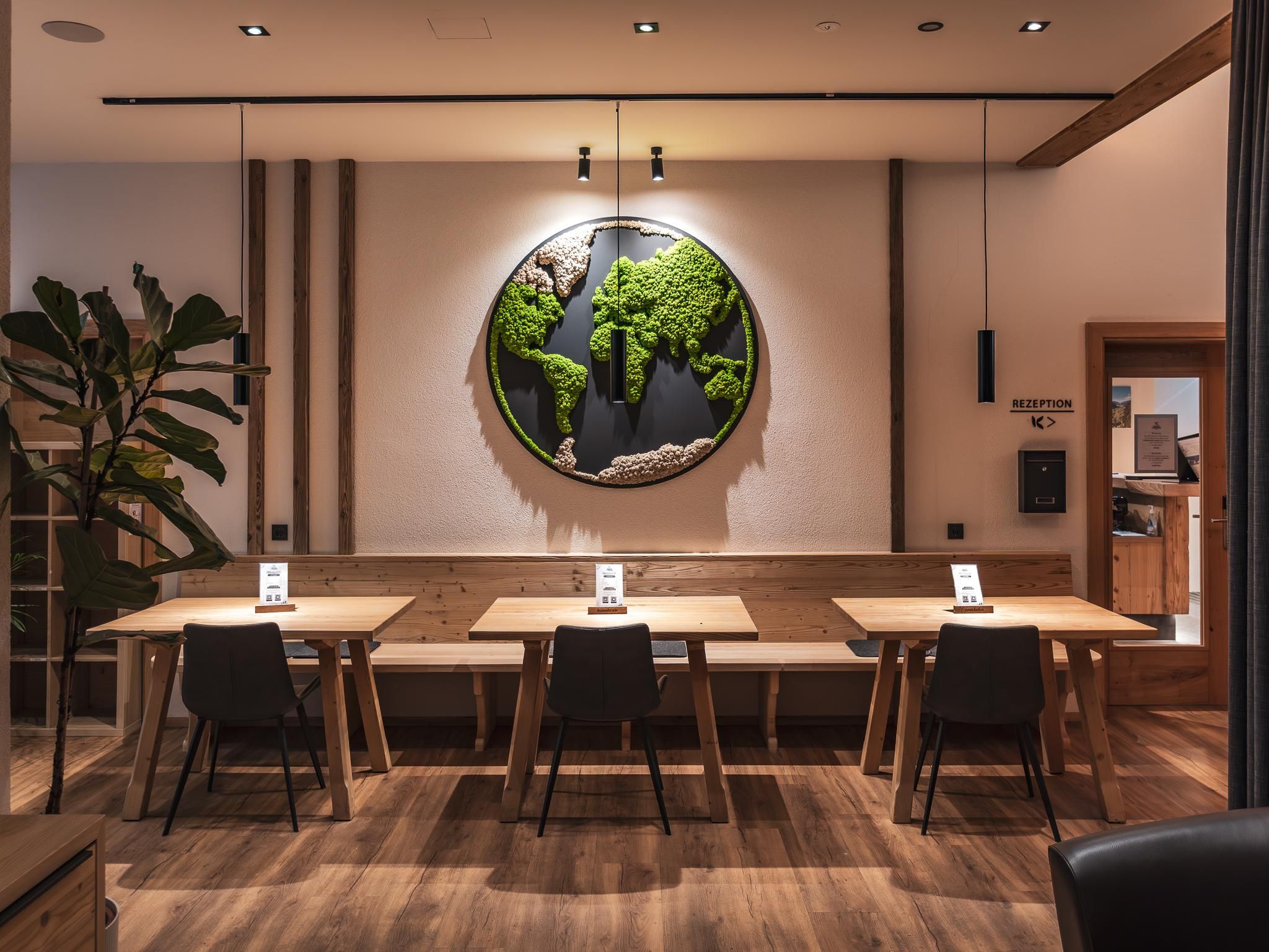 A modern café with wooden panels and elegant chairs. A creative mural featuring a green moss landscape hangs on the wall.