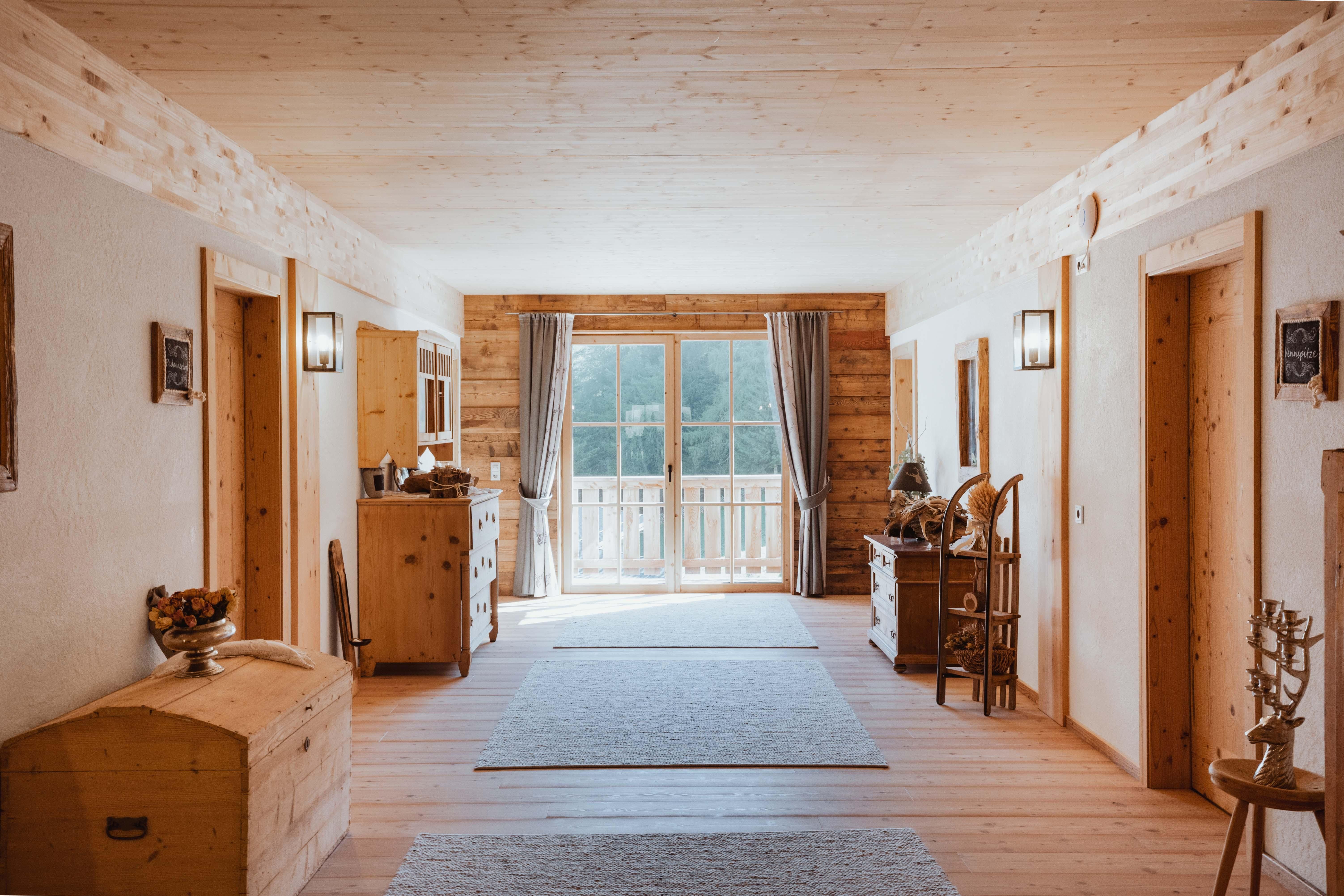 A cozy hallway with wooden walls and light carpets. Large windows let in plenty of light and offer a view outside.