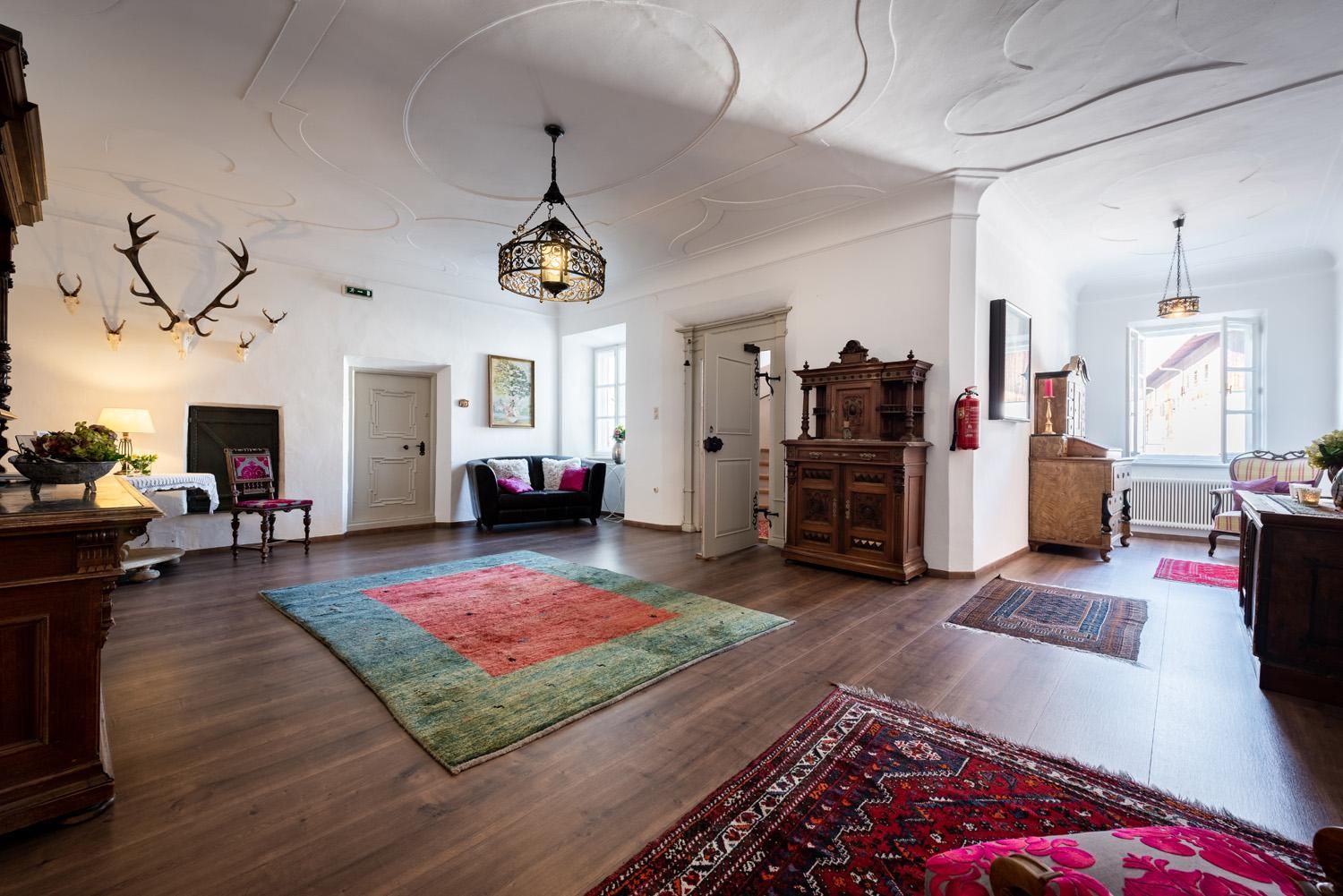 A stylish living room with wooden floors and elegant furnishings. Antique furniture and colorful rugs give the space character and coziness.
