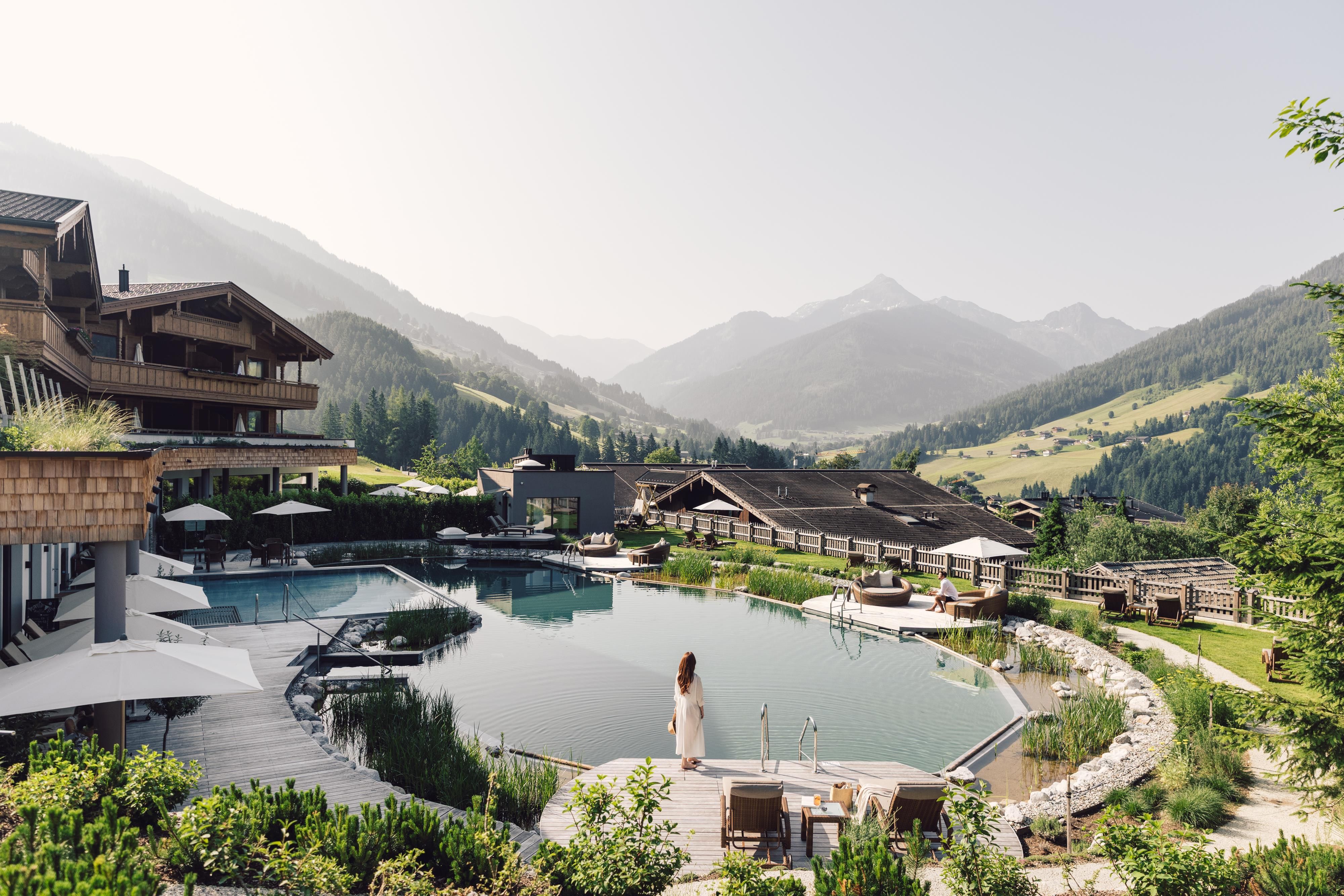 A beautiful mountain hotel with a pool and breathtaking mountain views. The green surroundings create a relaxing atmosphere.