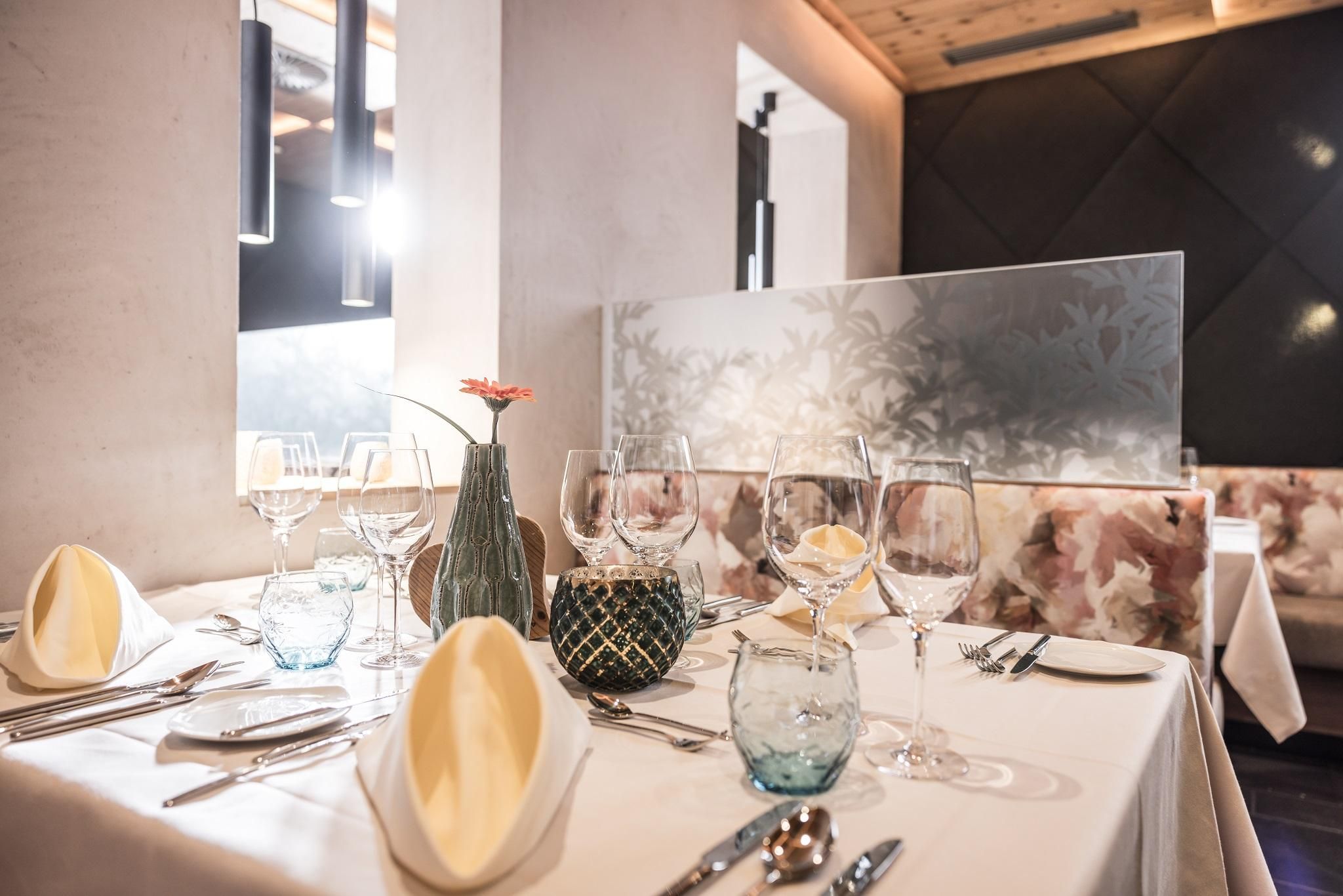 An elegant table in a restaurant with beautifully set dishes. There are glasses, cloth napkins, and a small bouquet of flowers in the center.