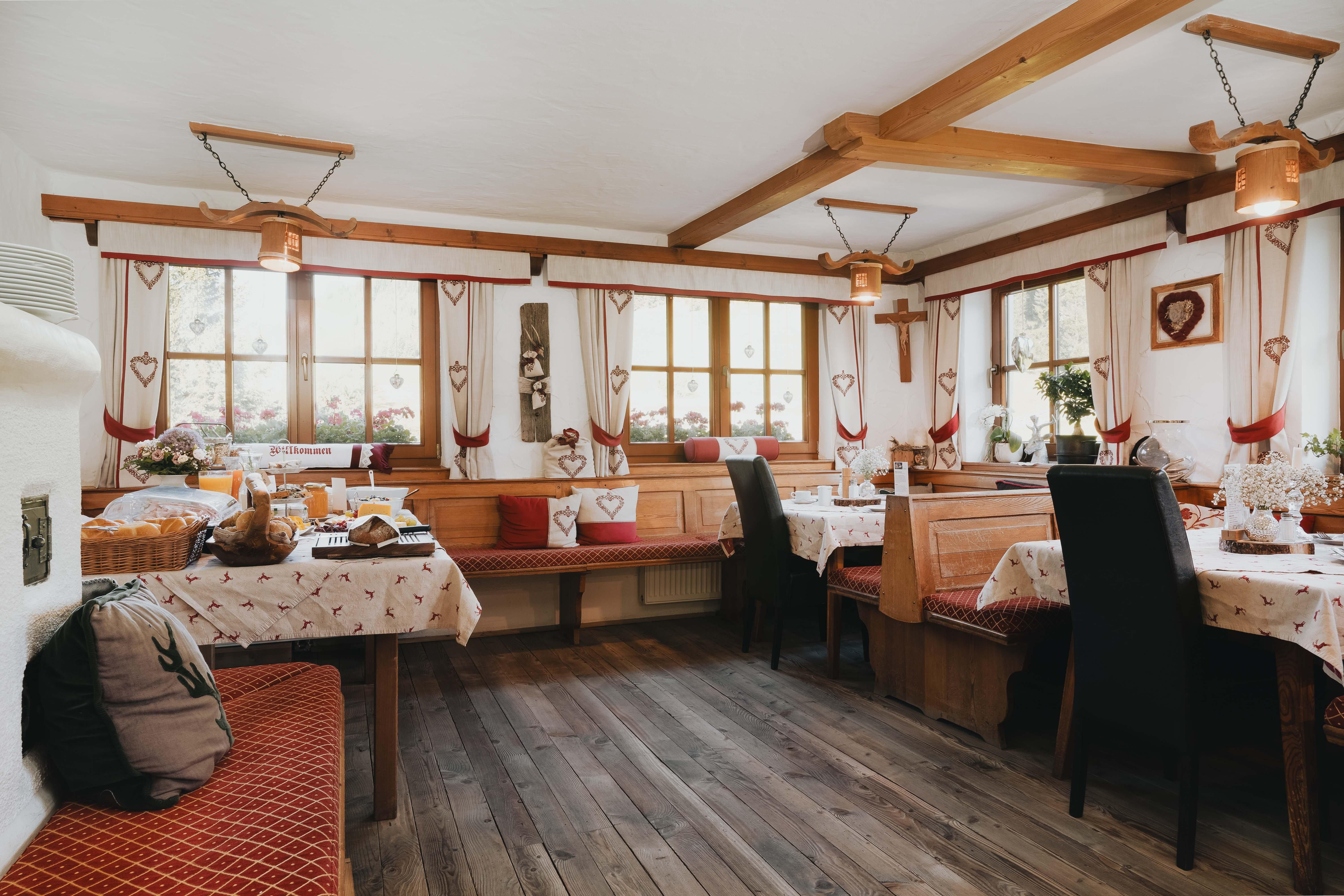 A cozy restaurant with wooden furniture and traditional tablecloths.
Large windows let in plenty of light and offer a view of the flowers outside.
