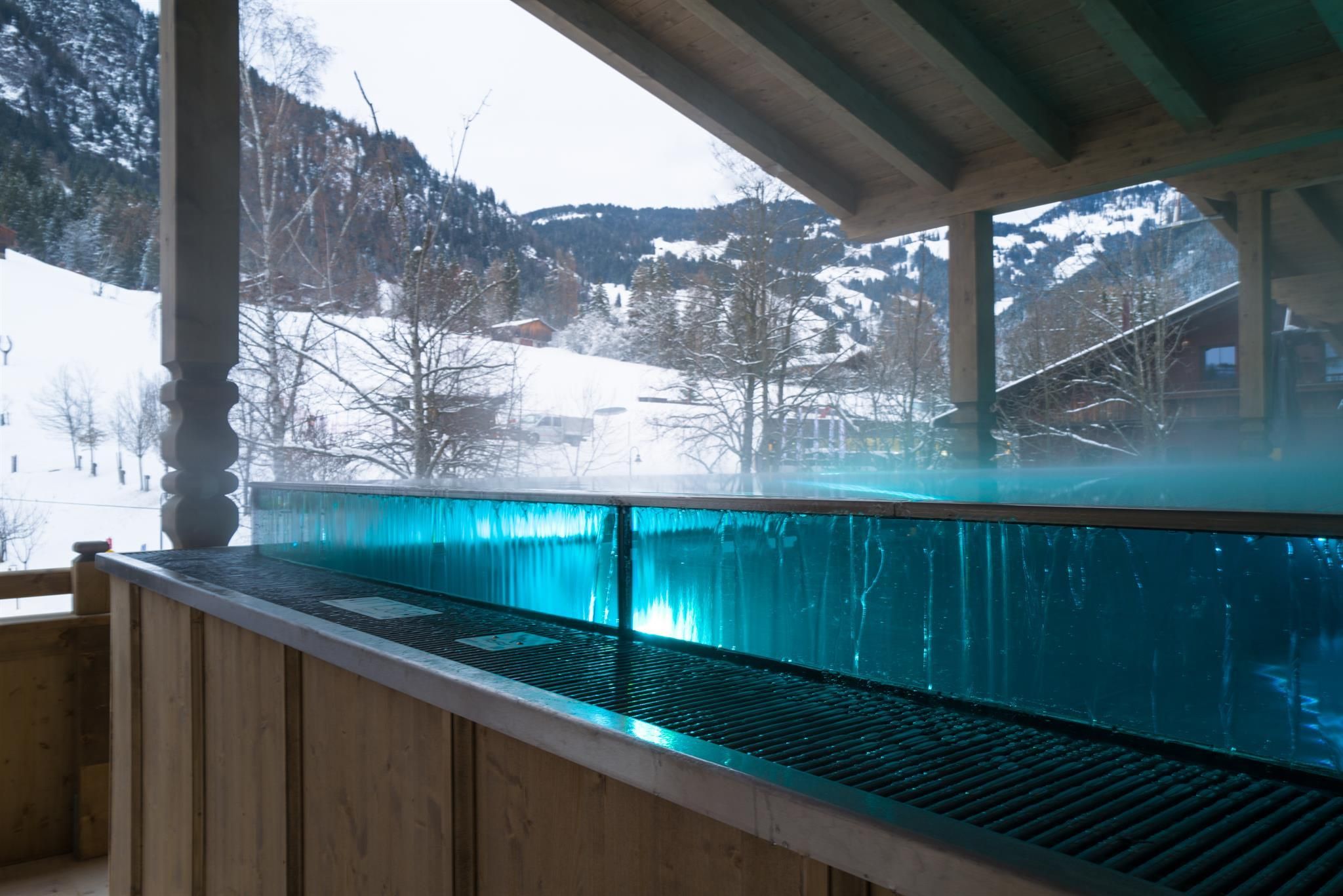 A stylish interior with a heated whirlpool, surrounded by snow-covered mountains. The view invites relaxation.
