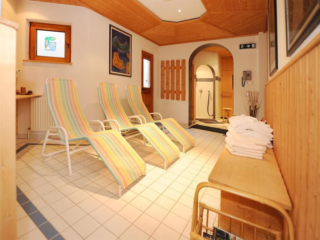 A relaxing room with deck chairs in colorful stripes. In the background, towels and a shower can be seen.
