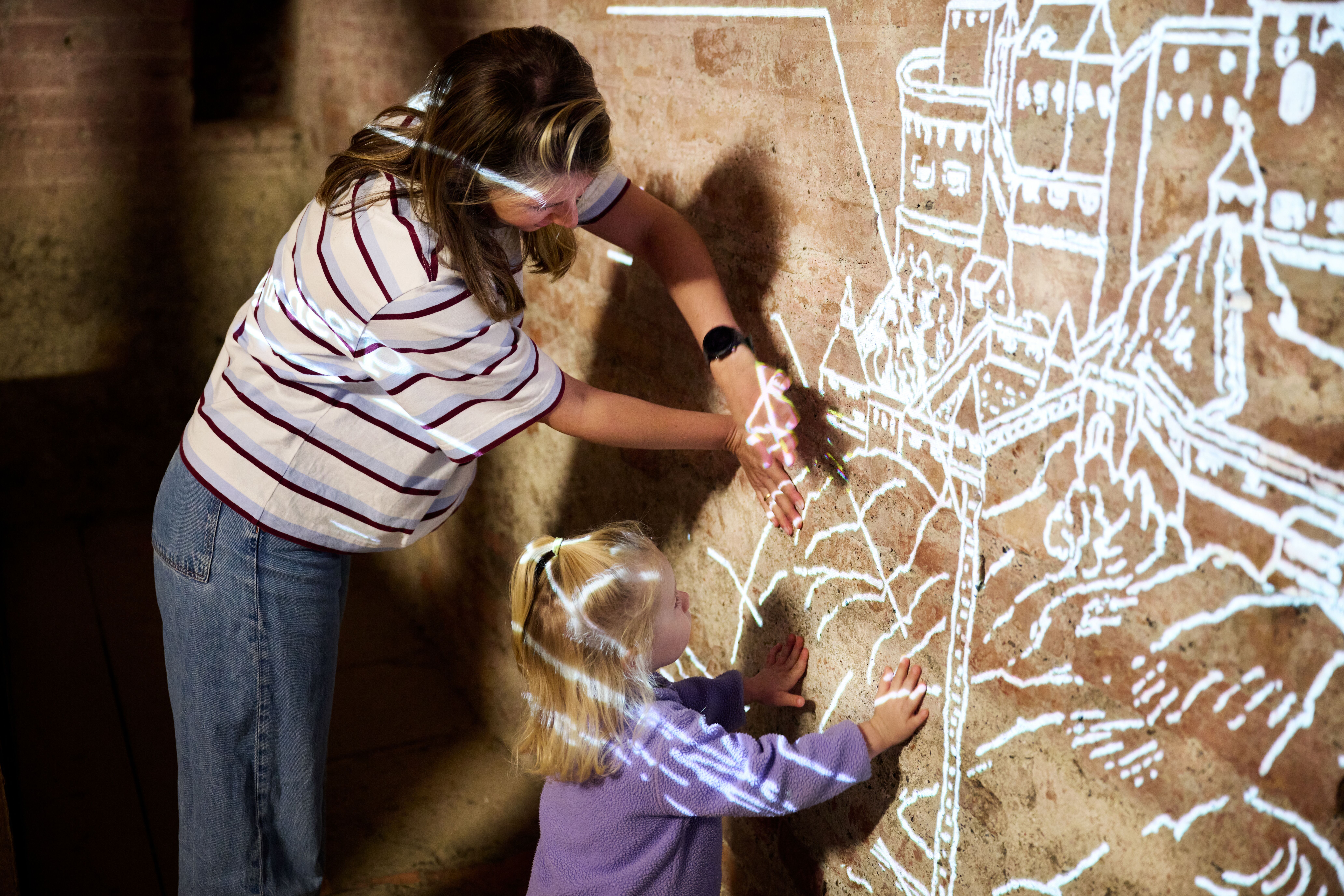 Frau mit Kind entdecken spielerisch eine Wandmalerei von der Festung Kufstein