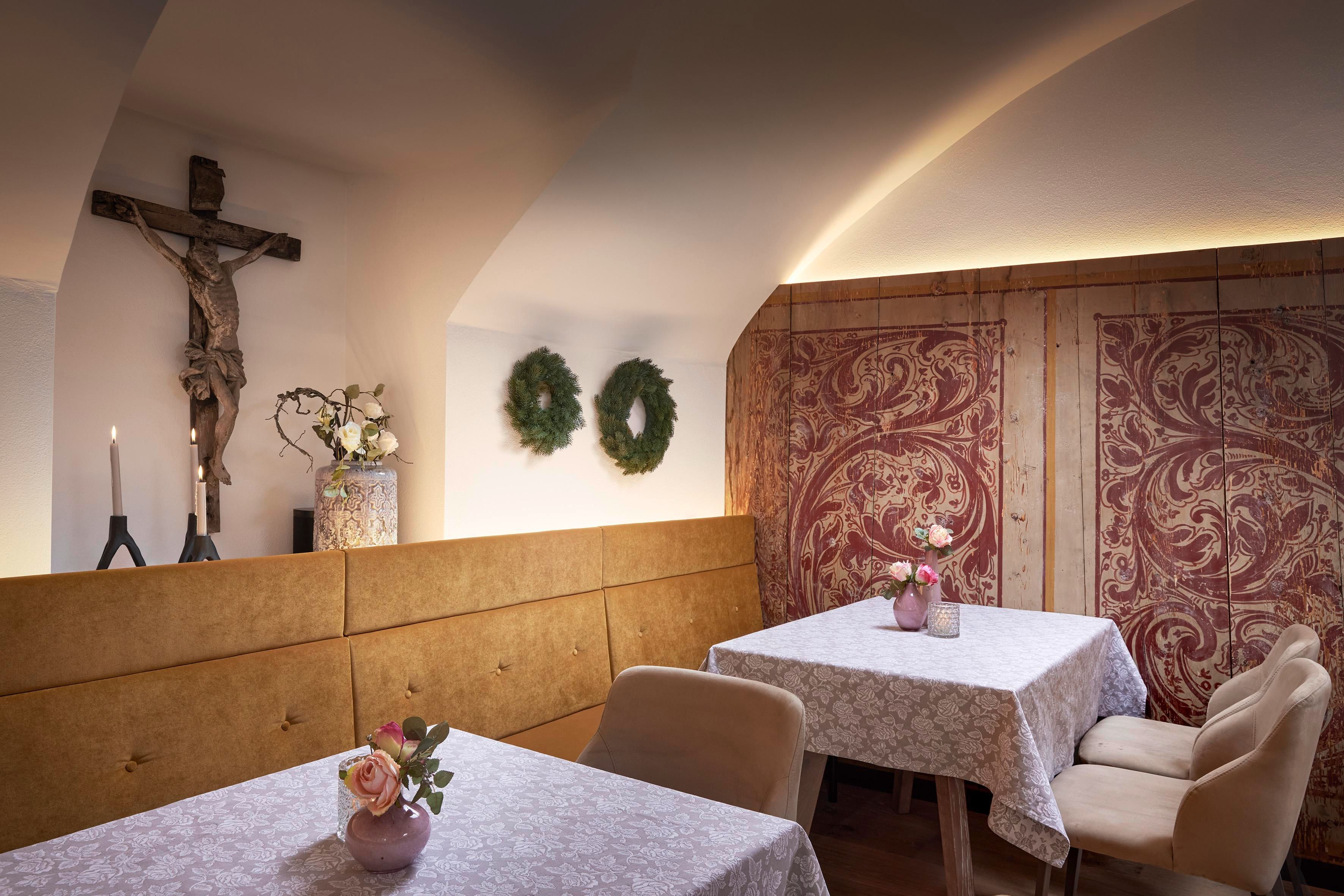 A cozy restaurant with elegant tables and a warm atmosphere. Decorative elements and a cross hang on the wall.