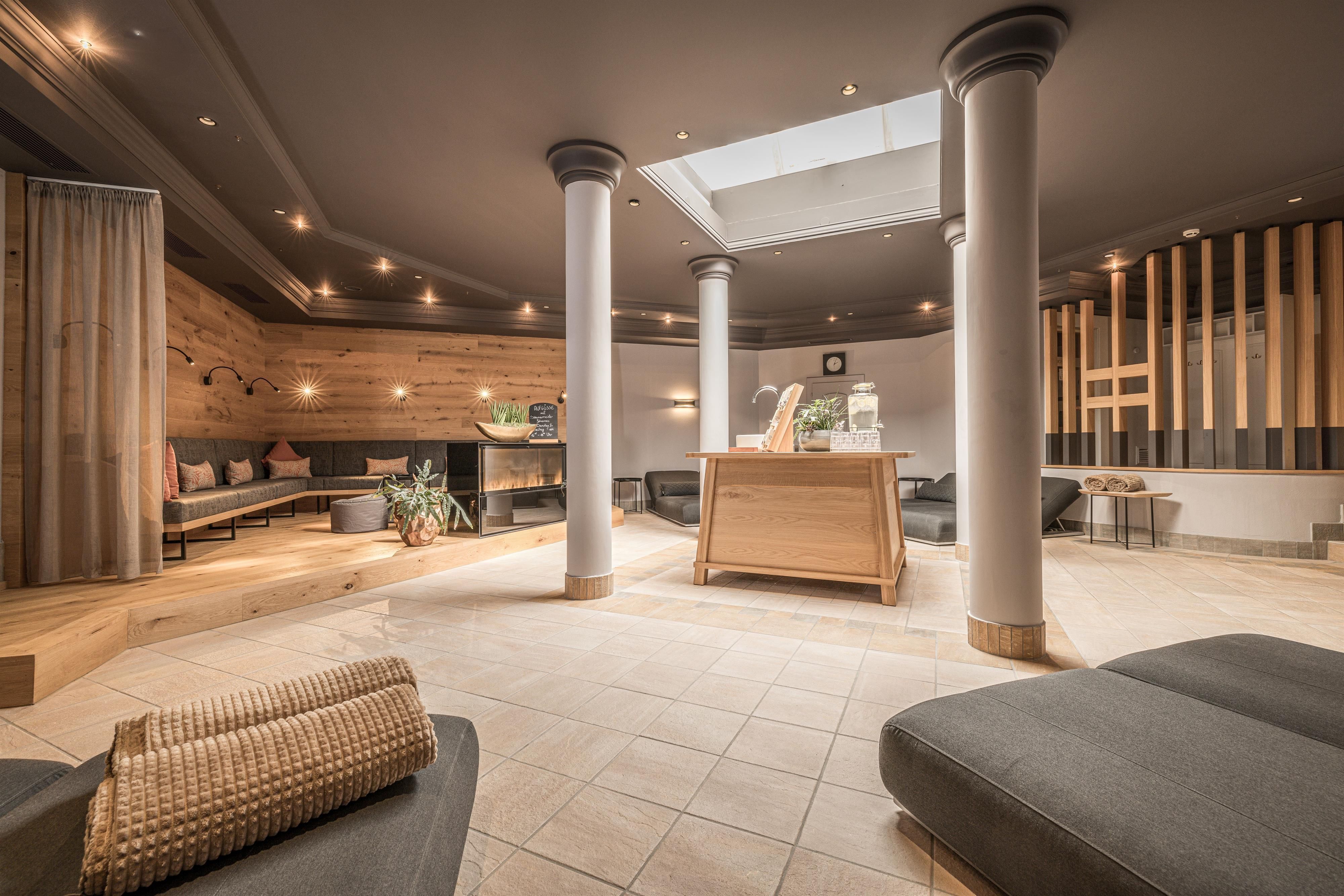 A modern reception area featuring wooden elements and comfortable seating. Large windows provide plenty of daylight and a relaxed atmosphere.