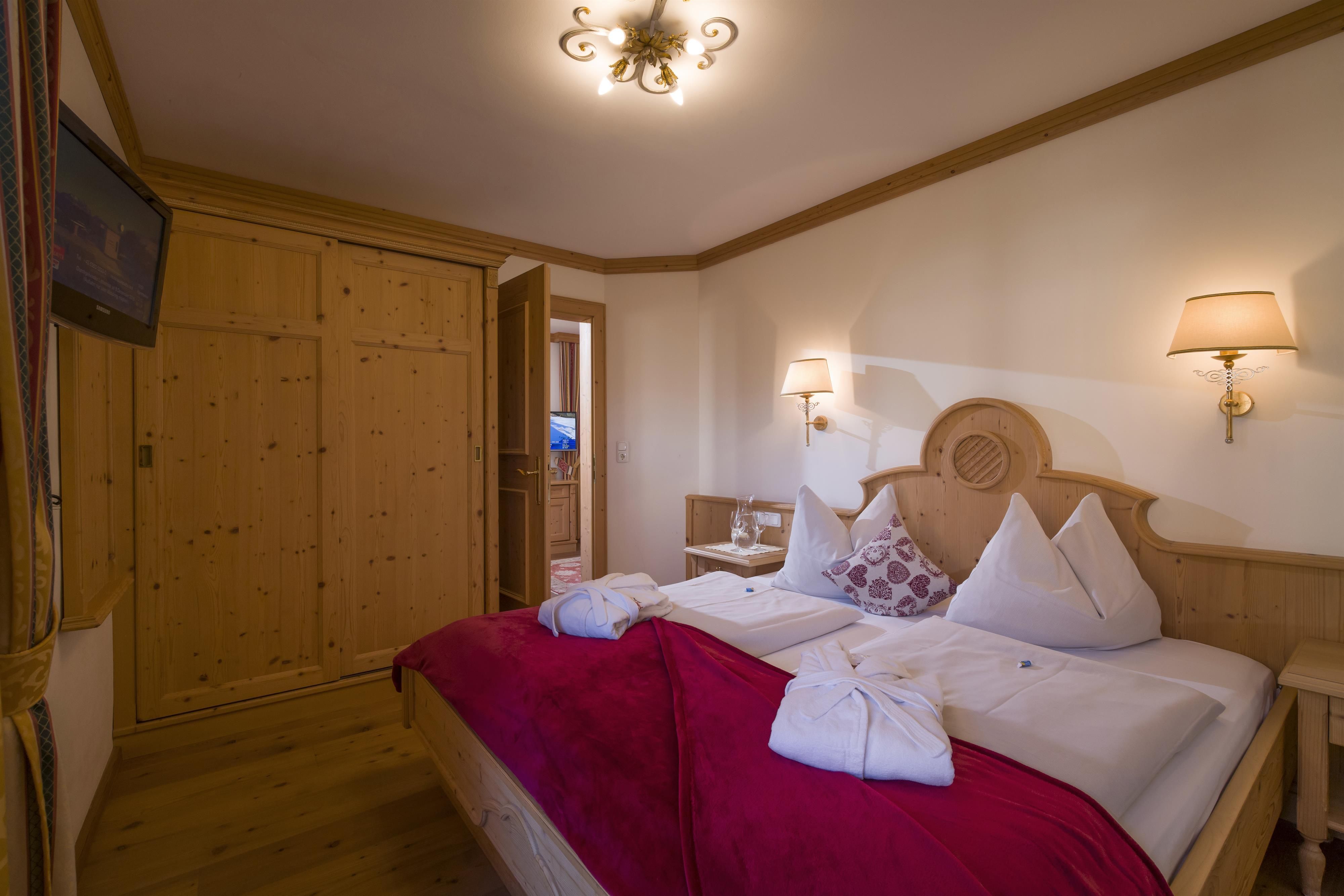 A cozy bedroom with a double bed and wood paneling. The room is brightly lit and has a warm, inviting atmosphere.