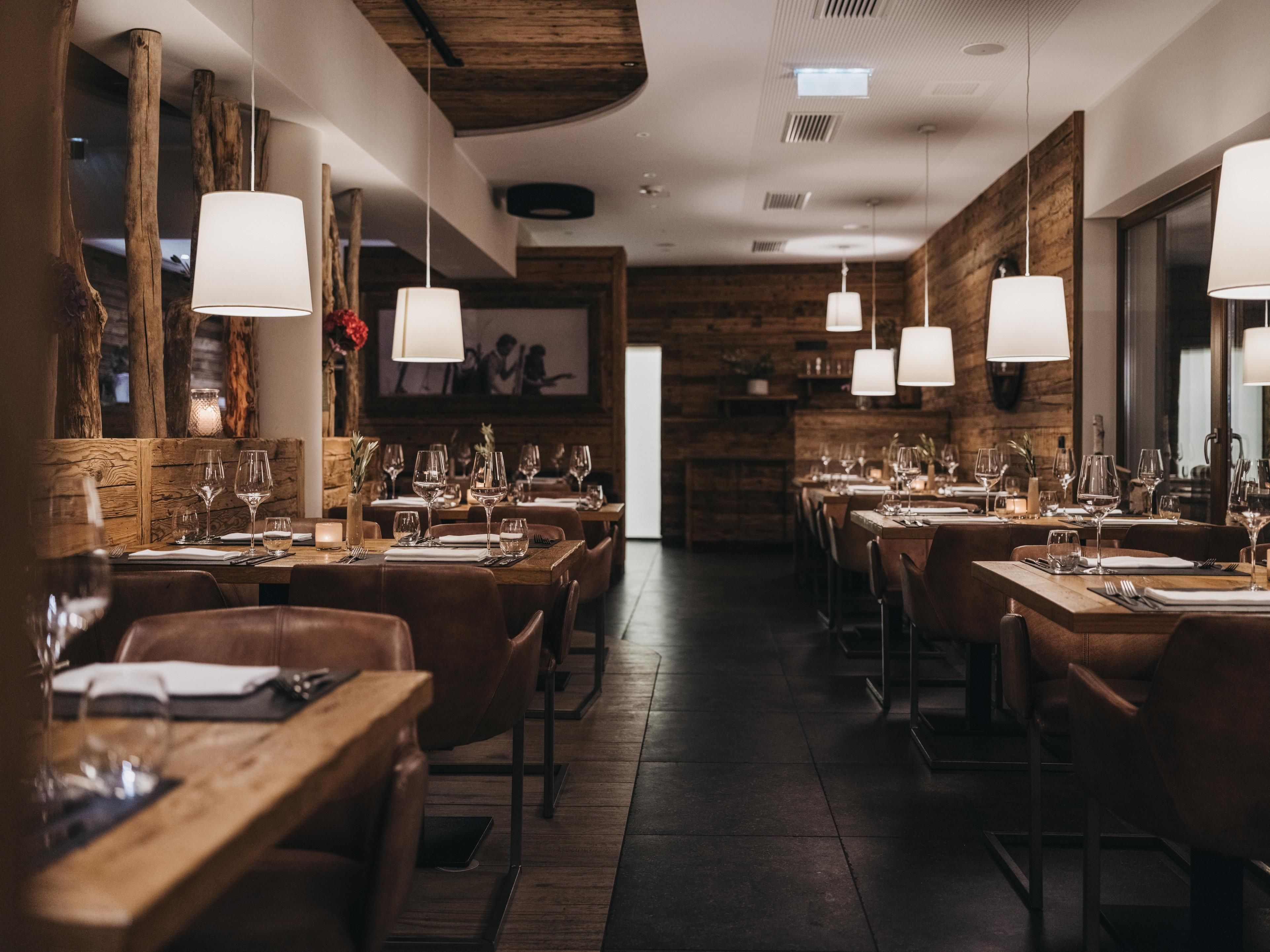 A cozy restaurant with wooden furniture and soft lighting. The tables are elegantly set and radiate an inviting atmosphere.