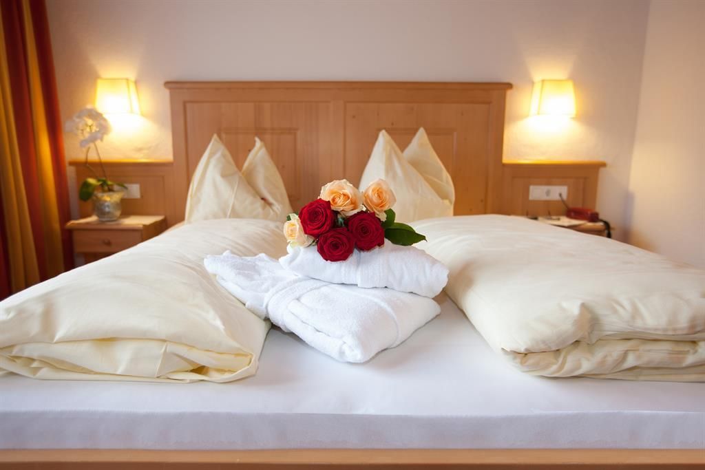 A cozy bedroom with a large bed and soft pillows. On the bedspread lies a bouquet of flowers and fresh towels.