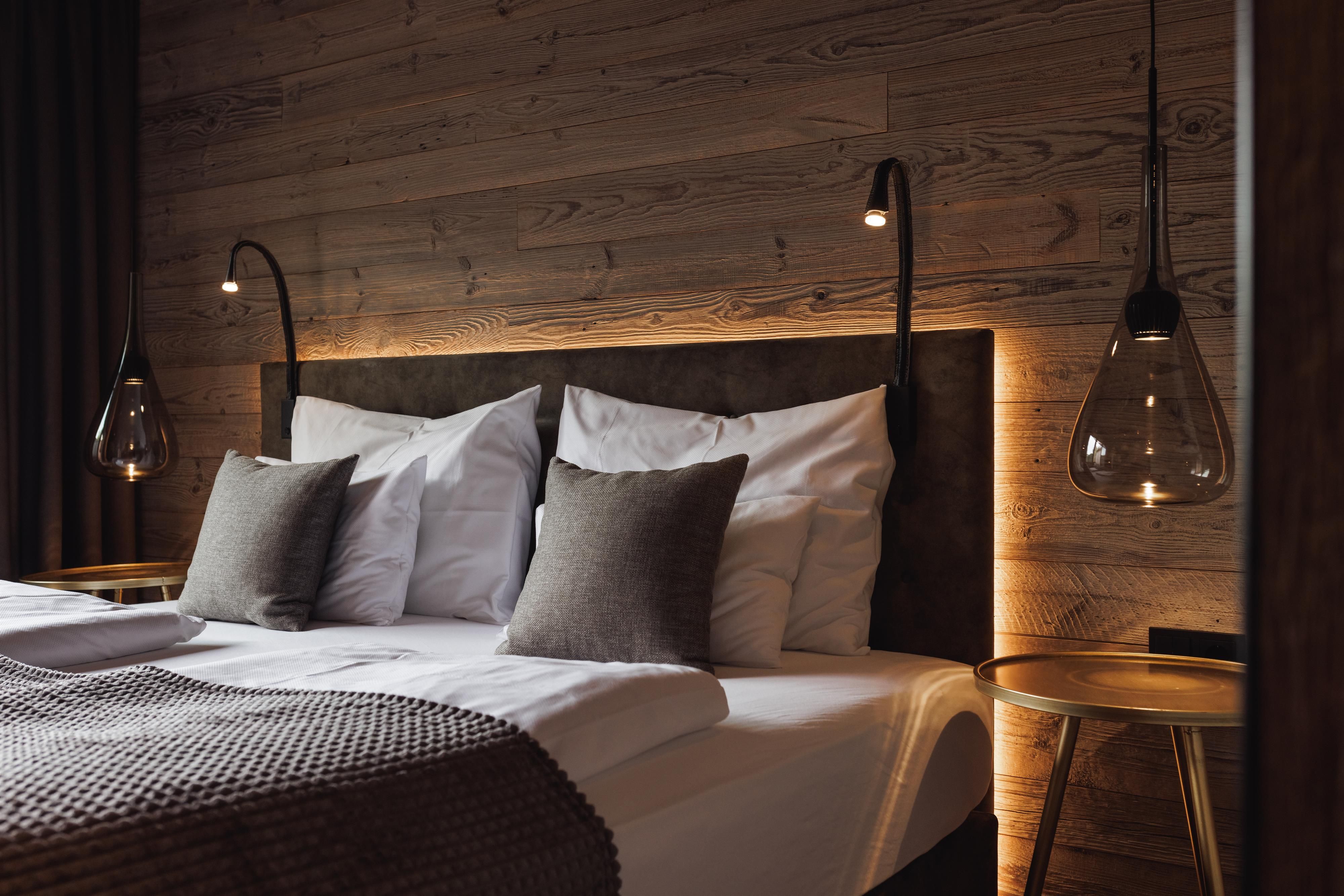 A modern bedroom with a large bed and soft lighting. The walls are made of wood, and the decoration is stylish and cozy.